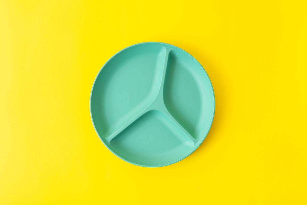 A green plate with divided sections on a yellow background. 