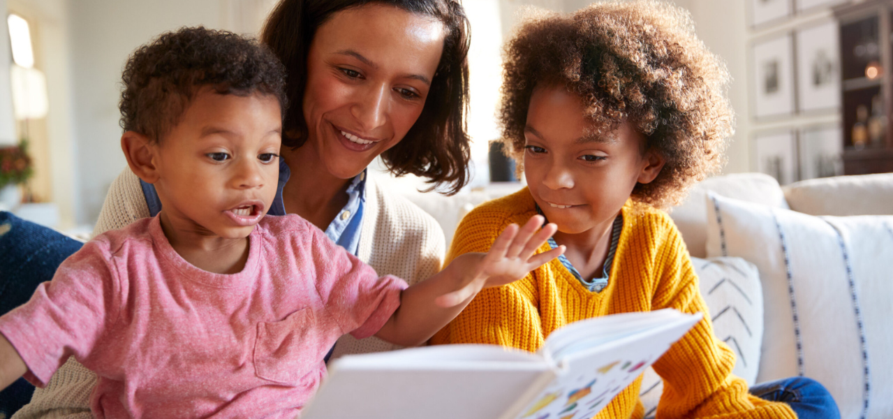 A young mom reading rhyming books to her young children. 