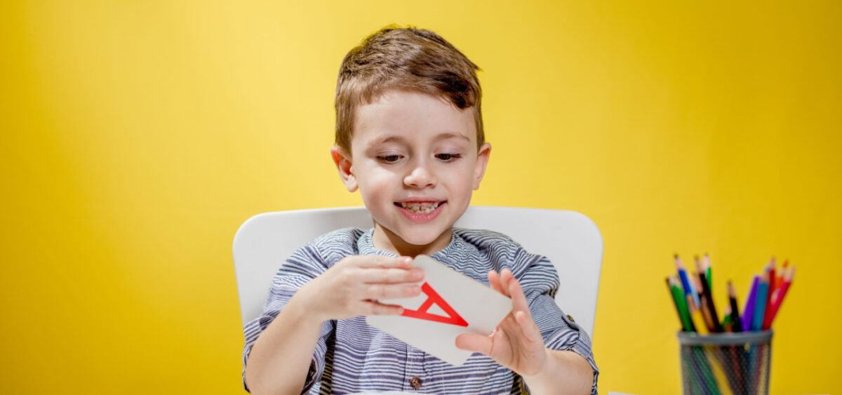 Boy playing with an alphabet card. 