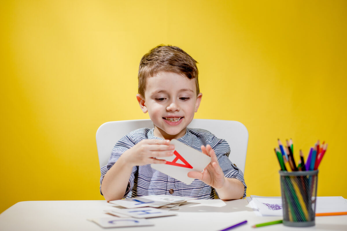 Boy holding a letter A flashcard. 