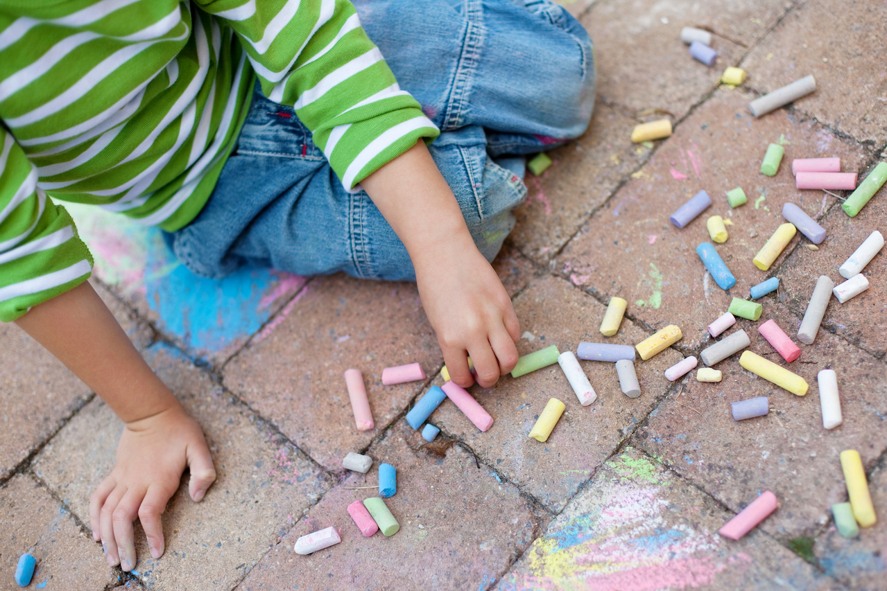 A young boy coloring with chalk. 