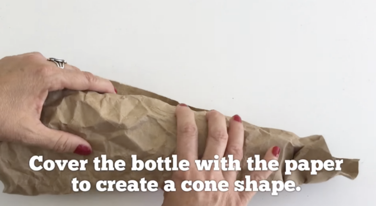 Wrapping textured paper around a bottle. 