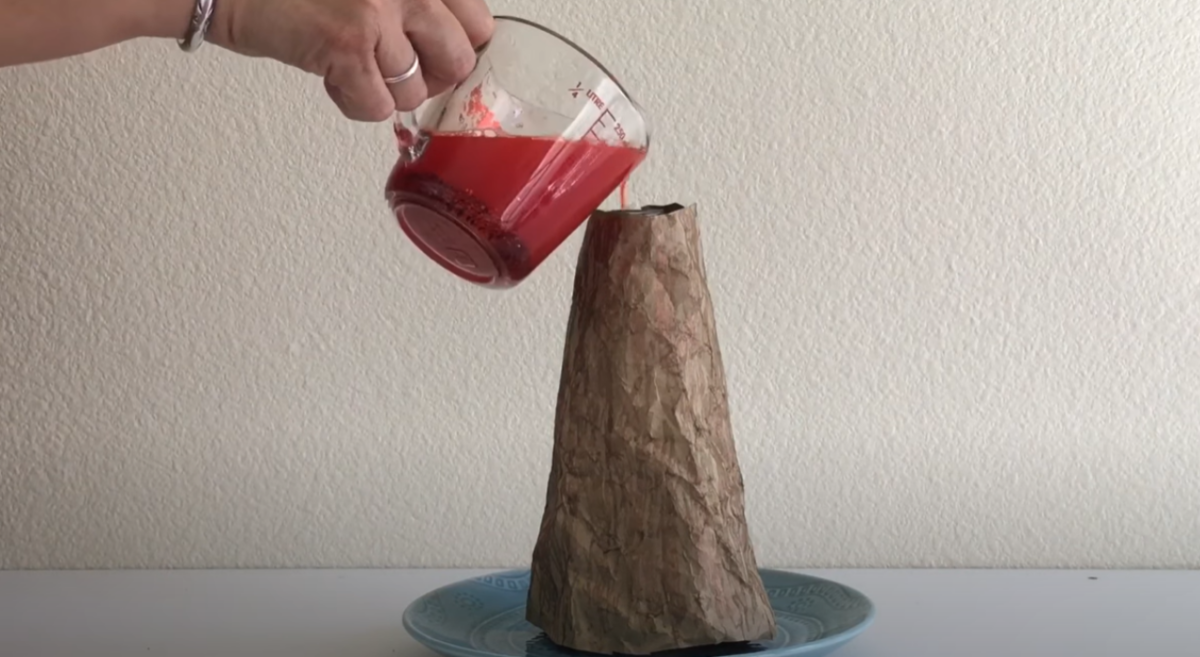 Pouring the lava mixture into the bottle to create a volcano eruption. 