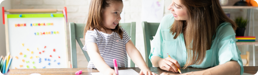 Young girl tracing words with her mother by her side. 