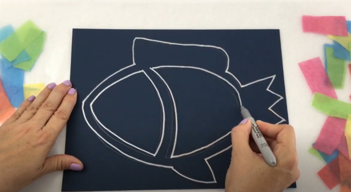 A black sheet of paper with an outline of a fish being drawn on it. 