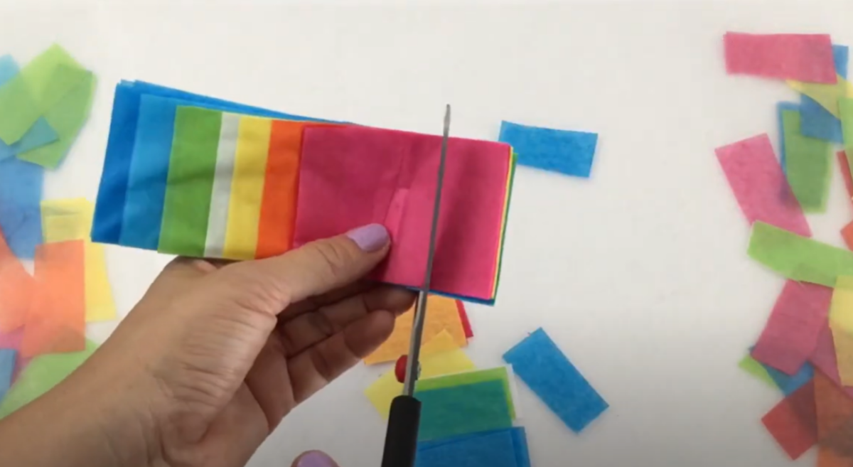 A stack of tissue paper being cut into squares. 