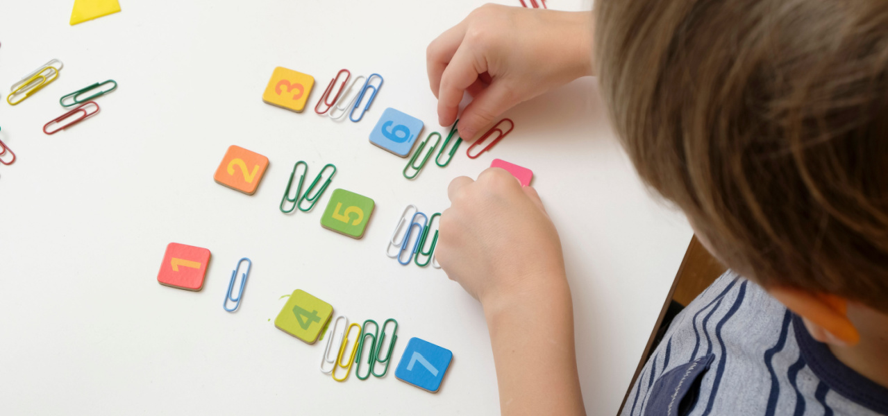 A young kindergartener counting paper clips 