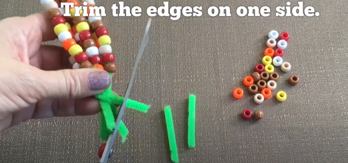 Trimming the end of the pipe cleaners off a bead craft corn on the cob. 