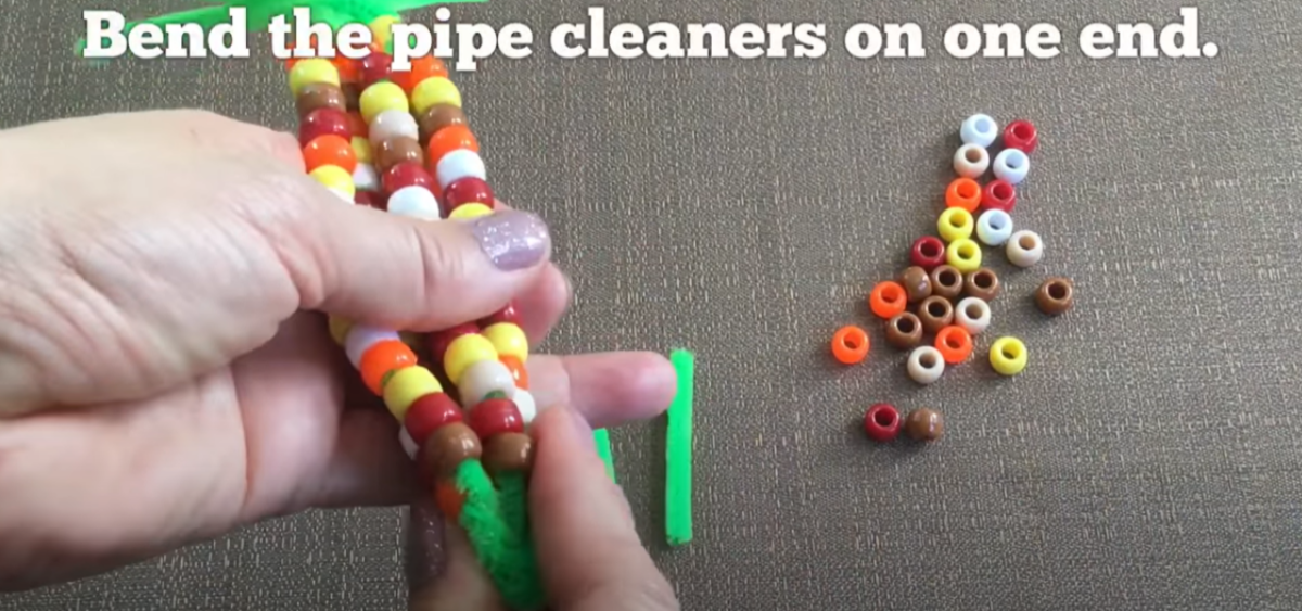 Bending the pipe cleaners up on a bead craft corn on the cob. 