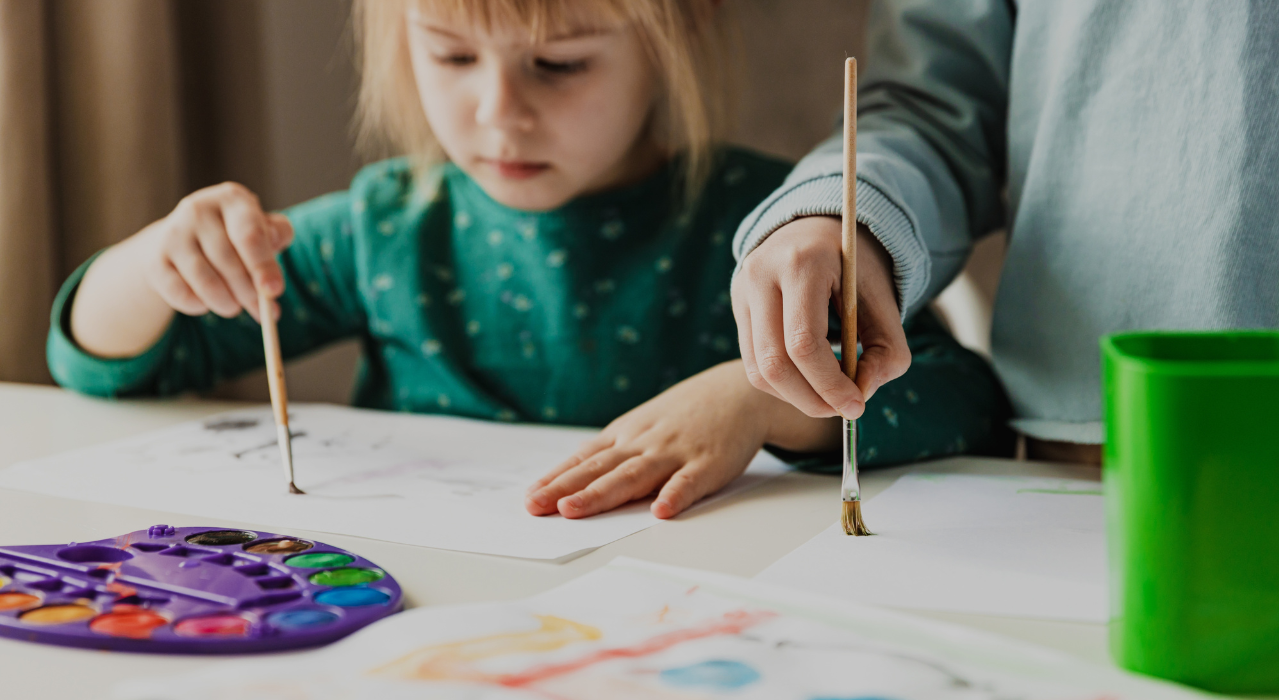 A girl and her brother painting with water colors. 