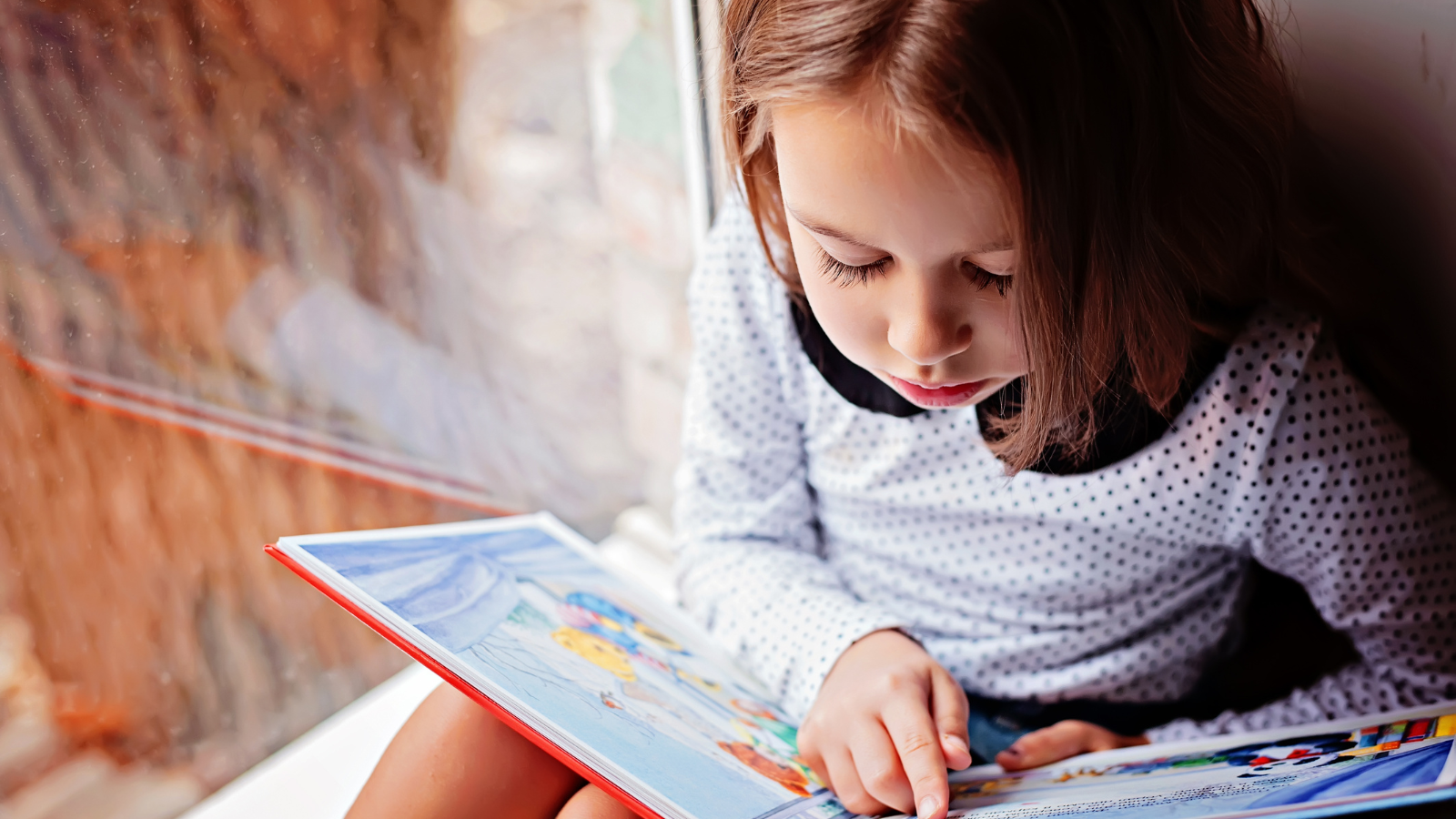 A kindergartener reading a book. 