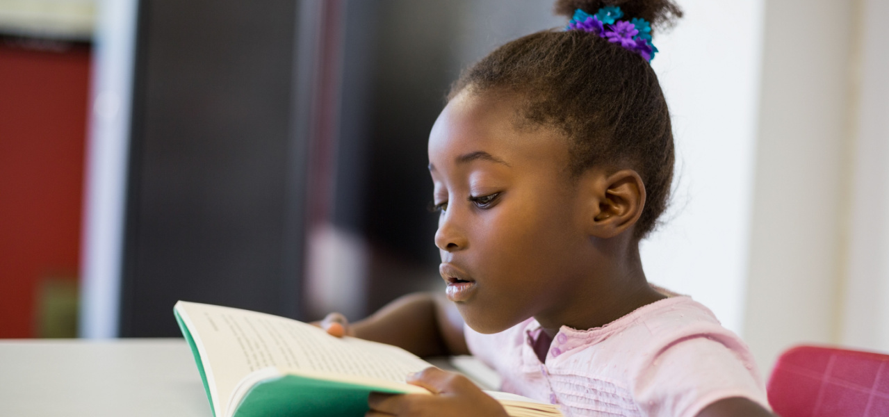 A second grade child reading a book independently. 