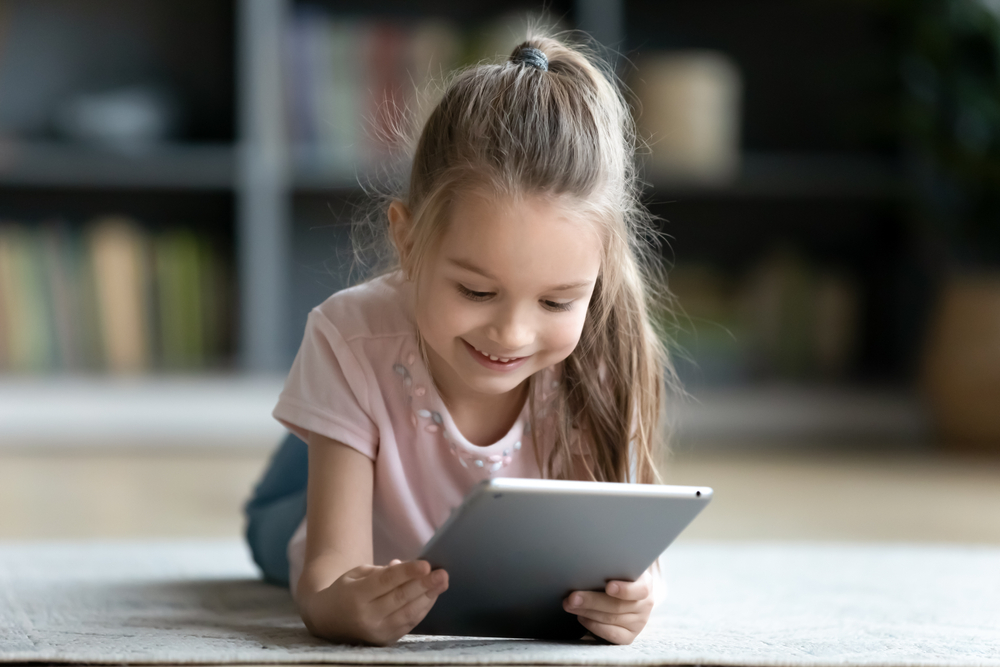 A young girl looking at an i-pad and smiling. 