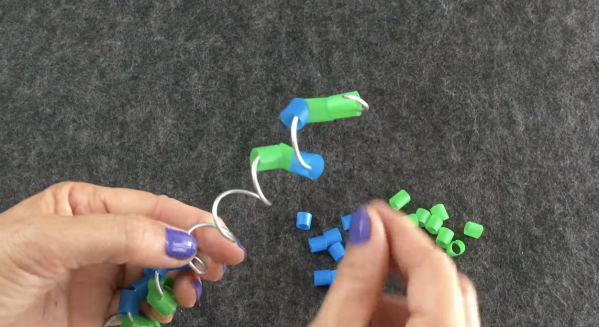 Threading pieces of straws onto a spiraled wire. 