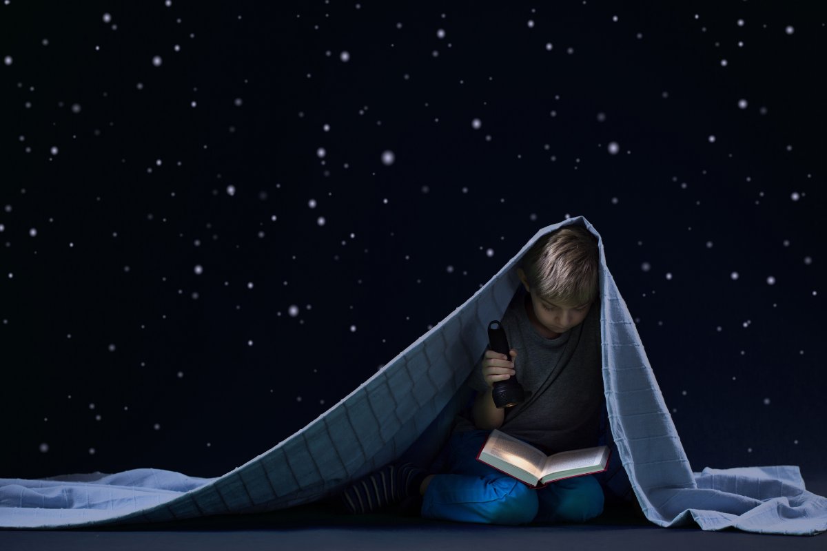 Boy reading under the stars. 