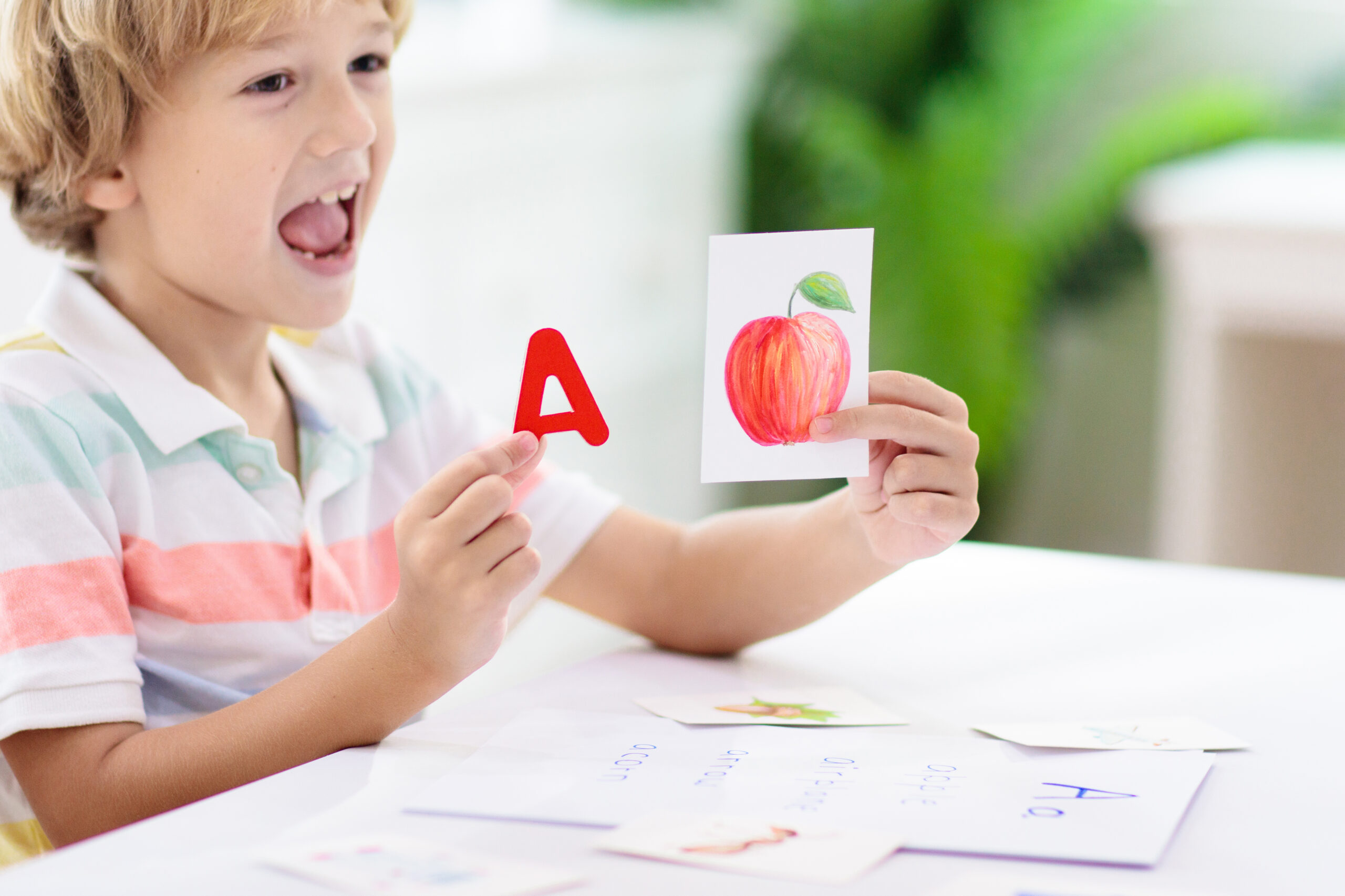 A young child sounding out the word apple while holding flashcards. 