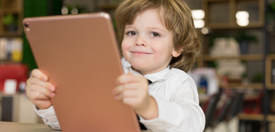 Young boy smiling holding an i-pad. 