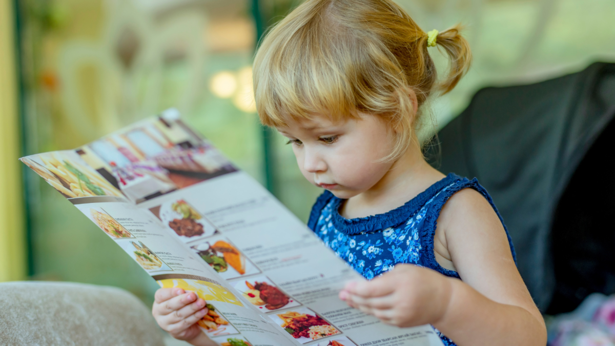 Young girl reading a menu.