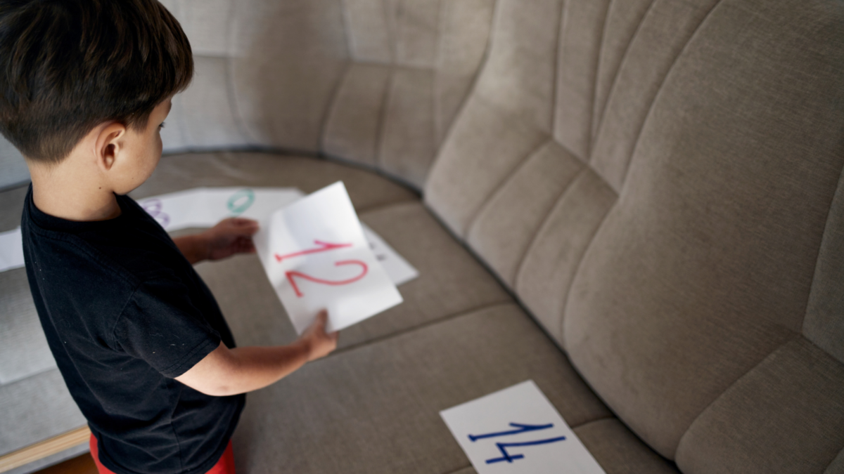 A young boy putting numbers written on papers in order. 