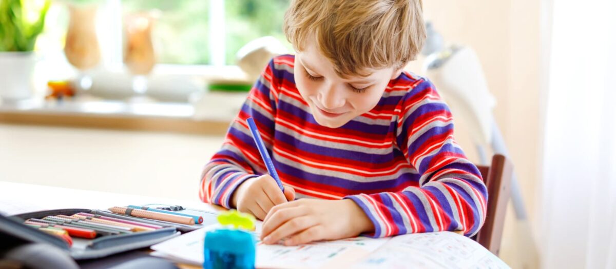 A young boy writing rhyming words in a notebook. 