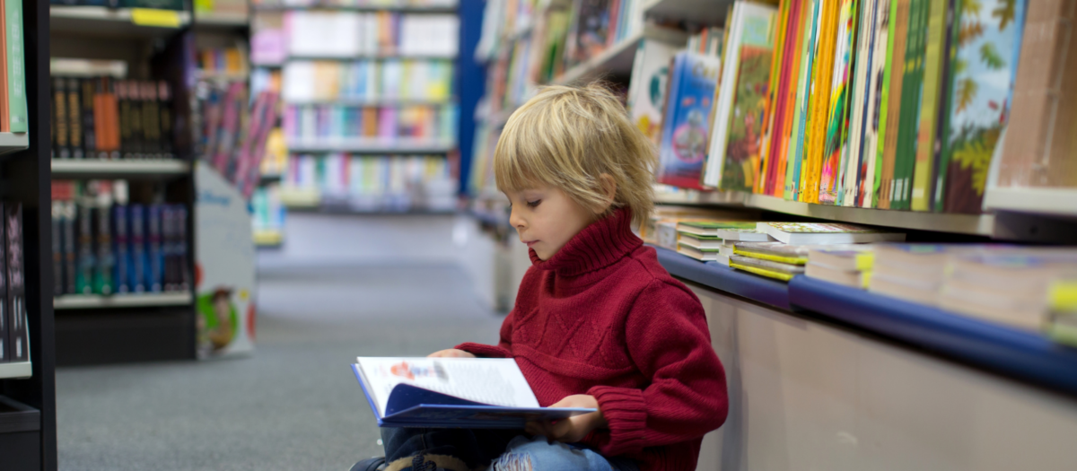 Young boy reading in a library. 