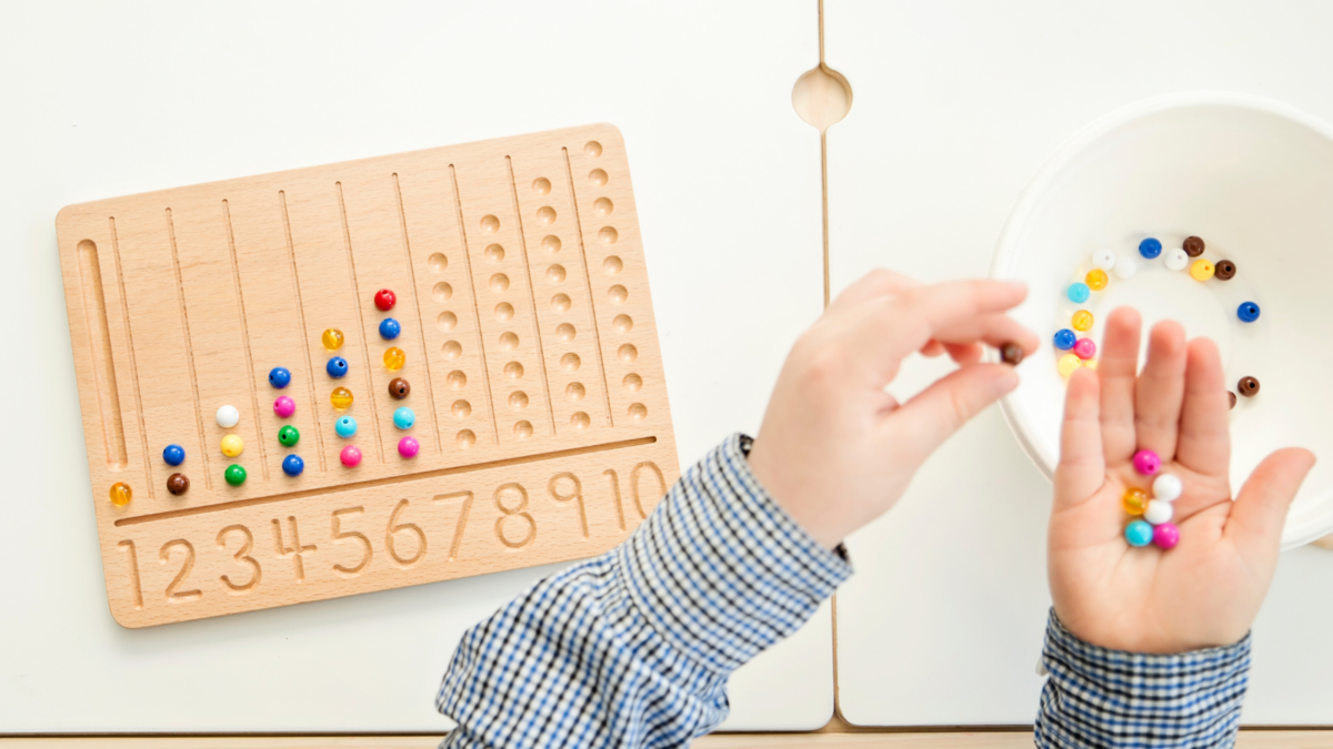 A child counting beads on a wooden number sheet. 