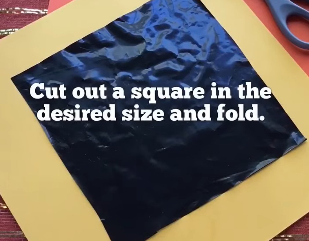 Cut a garbage bag into a square at the desired size for the spider web craft. 