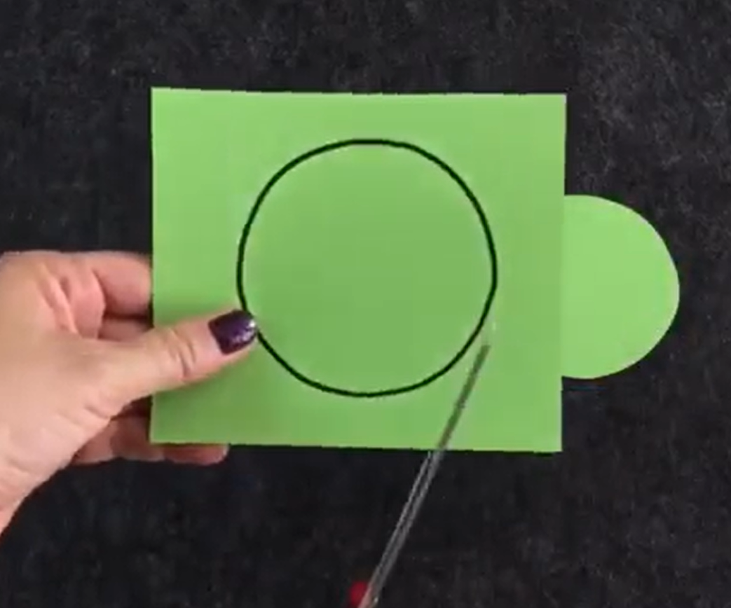 Cutting green construction paper into a circle. 