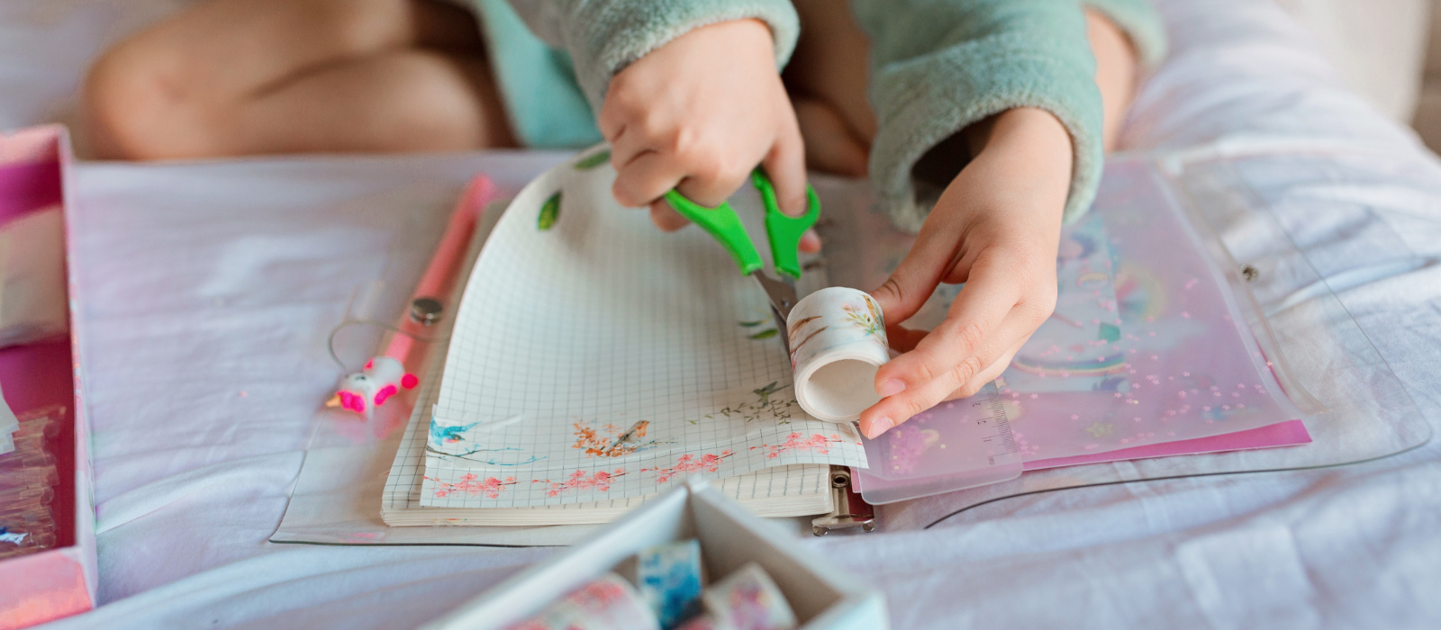 Young child making a book with stickers and scissors. 