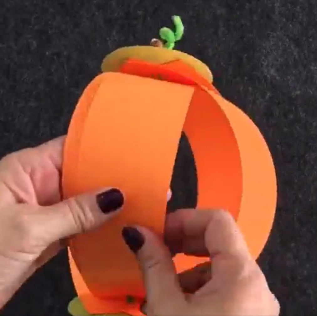 Spreading the construction paper into a circle to form a paper pumpkin. 