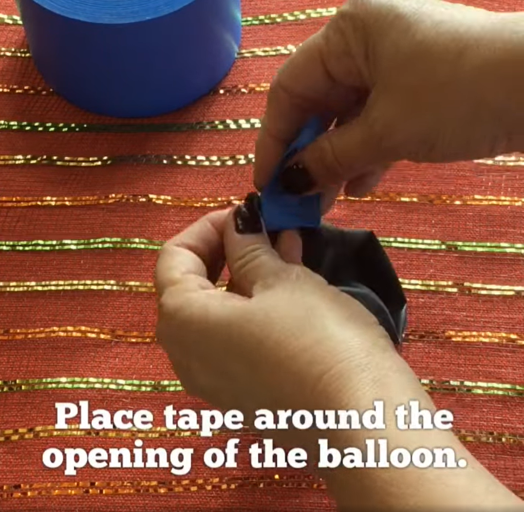 Place tape around the opening of a balloon to start with this Halloween bat craft activity. 