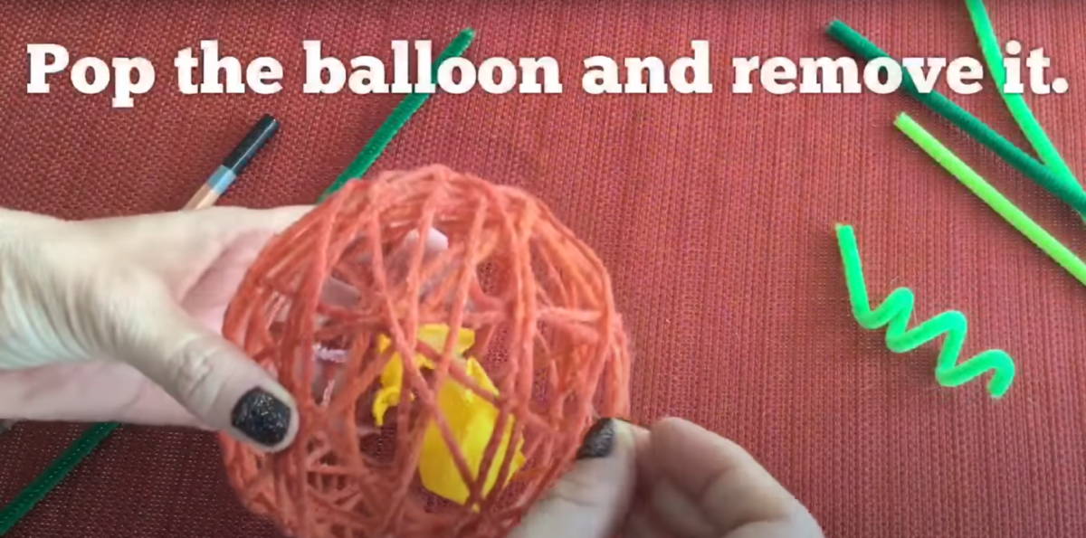 Pop the balloon and remove it from the yarn around it that has dried. 