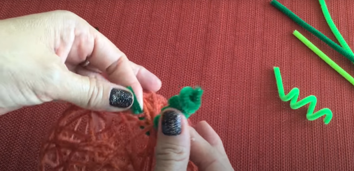 Adding the stem to a pumpkin yarn craft. 