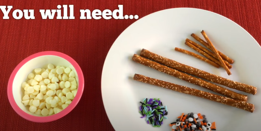 Ingredients to make Halloween Pretzel craft snack. White Chocolate, pretzels, and Halloween sprinkles. 