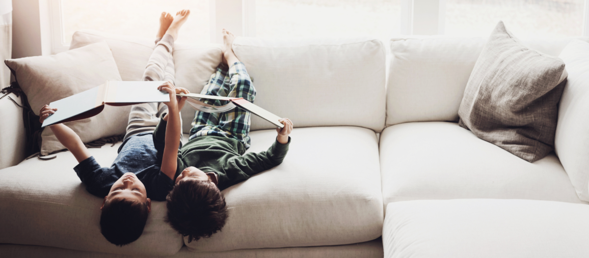 Two boys reading a book upside down. 