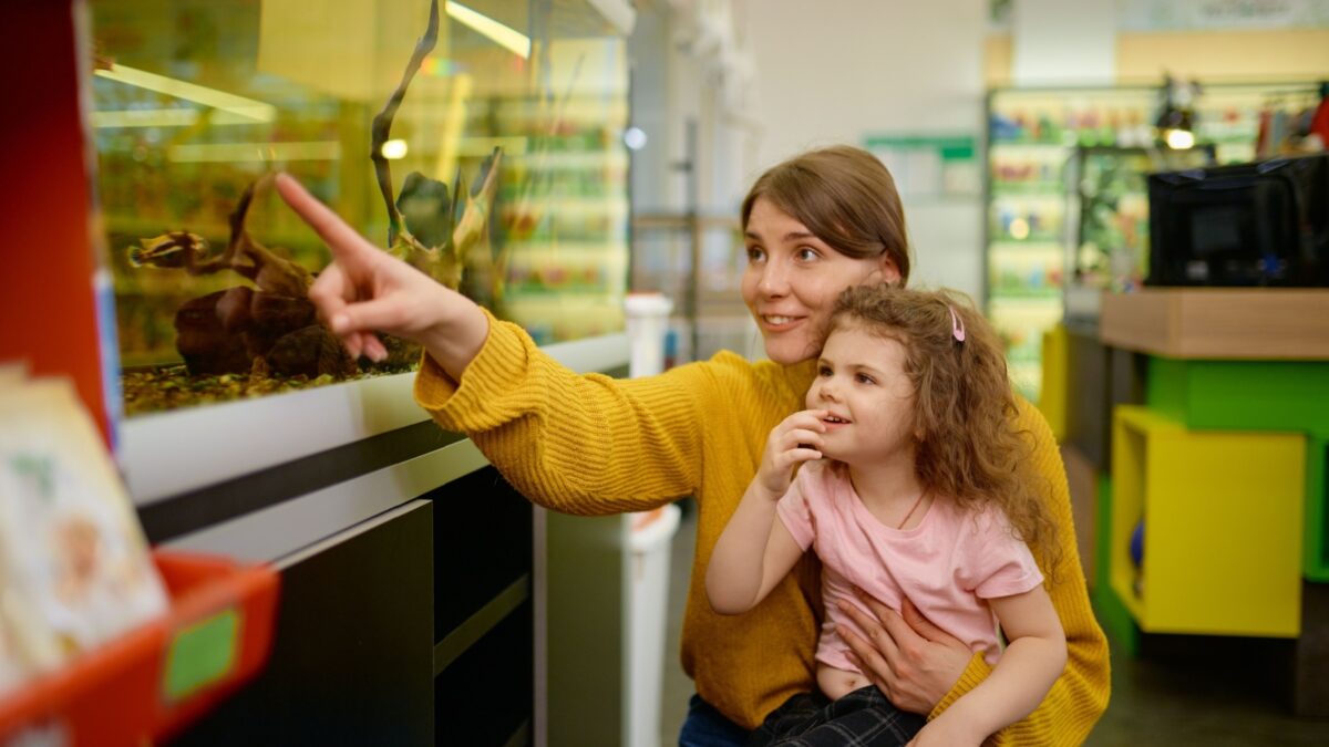 A mother and her child looking at fish in a fish tank. 