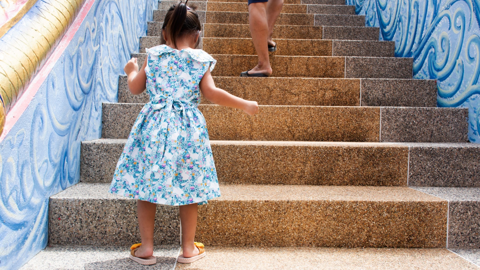 A young child counting stairs as she is climbing up them. 