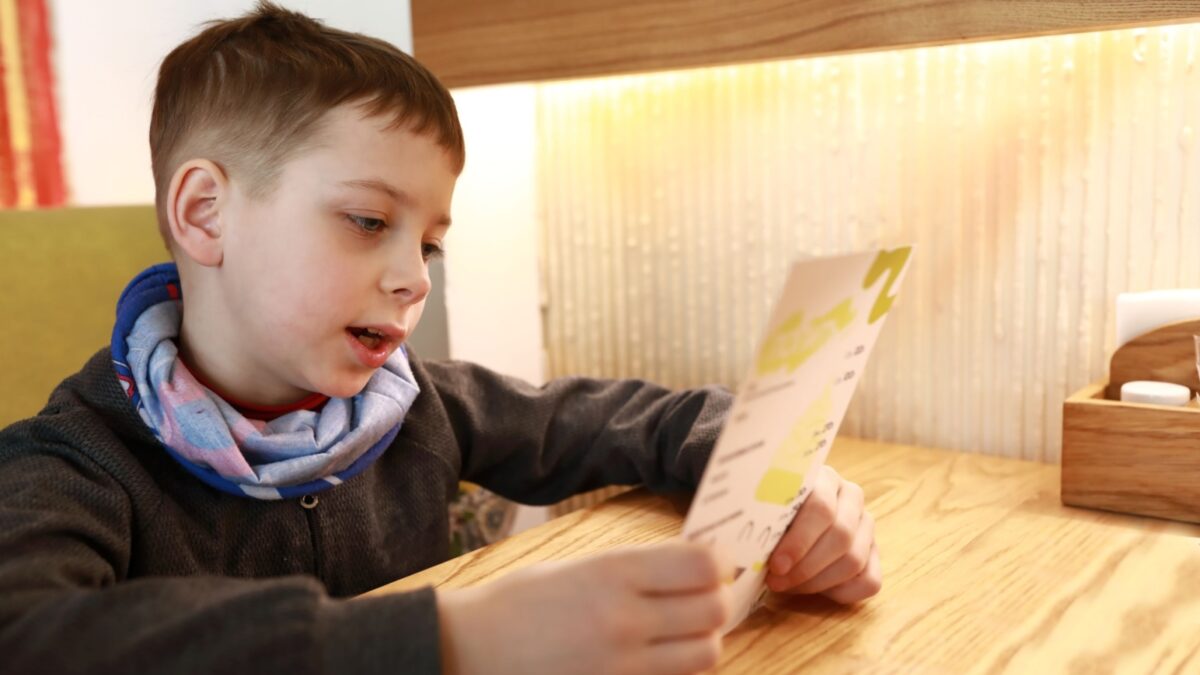 A child reading numbers off a menu. 