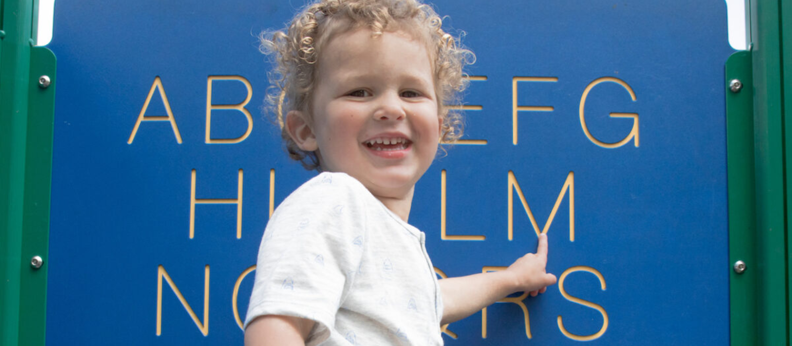 Young child pointing at an alphabet sign. 