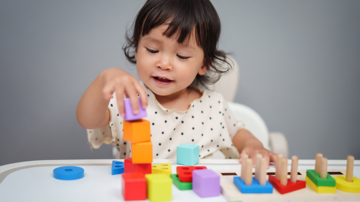 A young child counting and stacking blocks. 