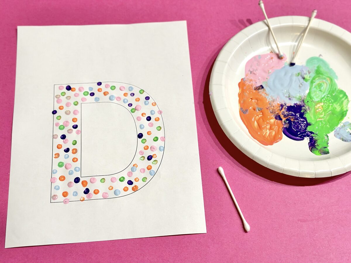 A large letter D with dots of colorful paint on it. 