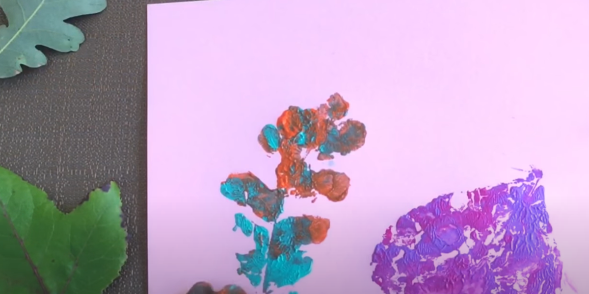 Colorful leaf prints on a light purple paper. 