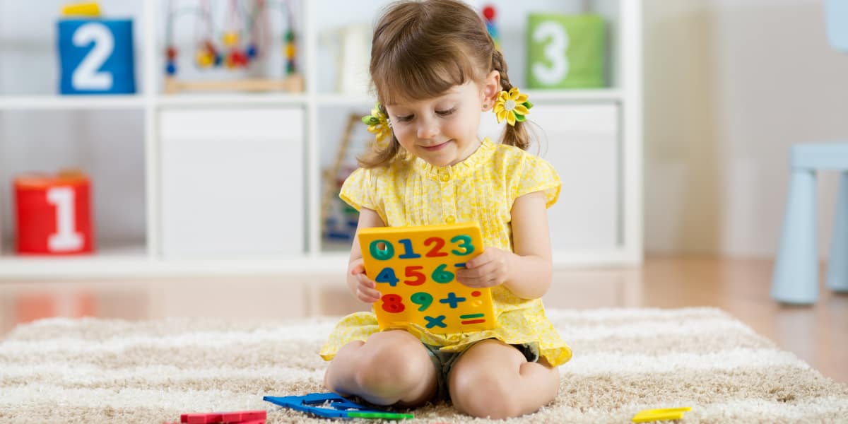 A young girl holding a colorful foam number toy.