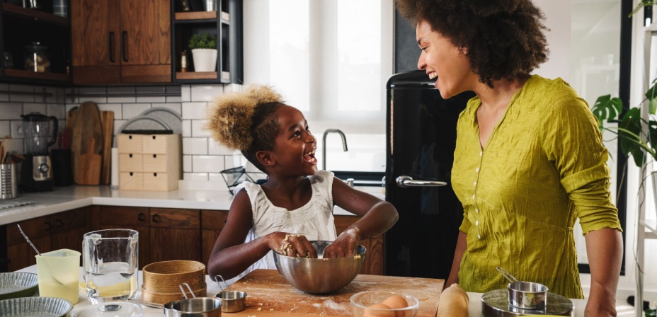 Child and mother in the kitchen cooking together. 