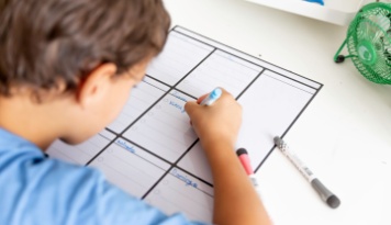 Child writing on a calendar. 