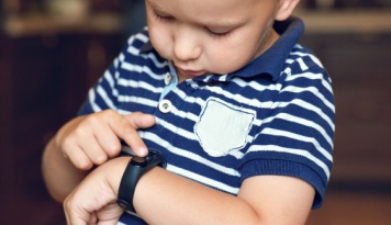 A small child looking at his watch. 