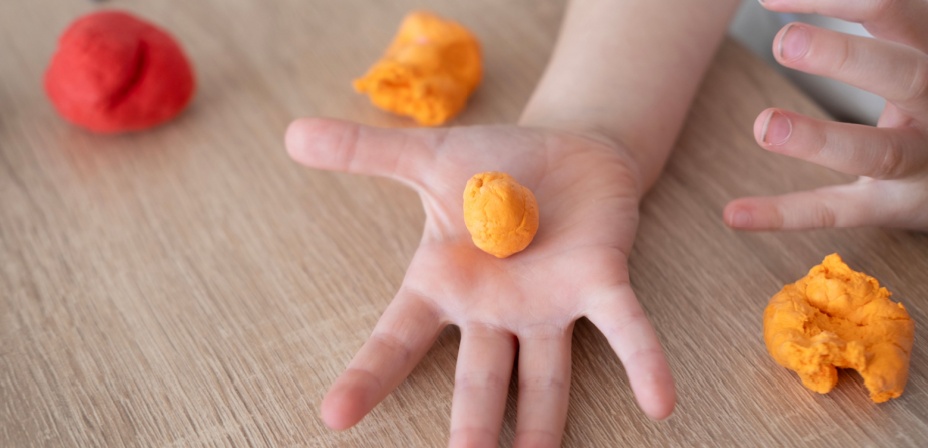 Childs hand holding a ball of play dough. 