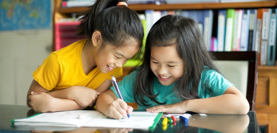 Children writing in a journal together. 