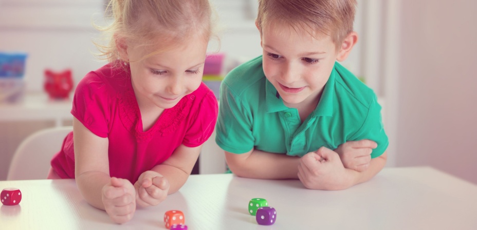 Children rolling dice for a fun vowel game activity. 