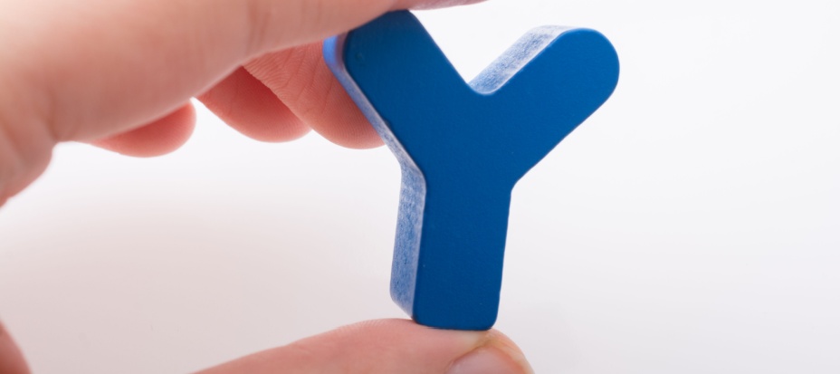 A child's hand holding a small blue letter Y. 